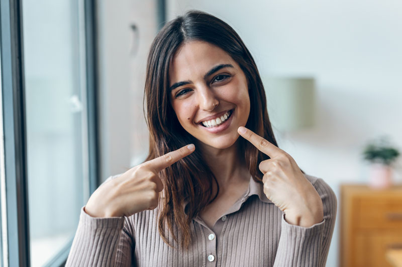 women with a beautiful smile pointing at her teeth